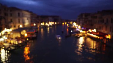 Rialto Köprüsü 'nden Büyük Kanal' ın Bokeh gece çekimi. Kanal boyunca güzel şehir ışıkları ve bulutlu, gece gökyüzünün altında renkli Venedik binaları. 4k