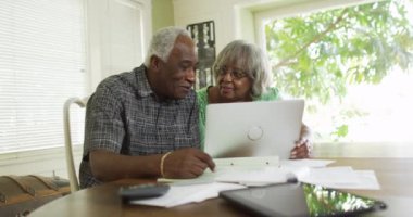 Mutlu yetişkin siyah çift laptoptaki faturaları ödüyor.
