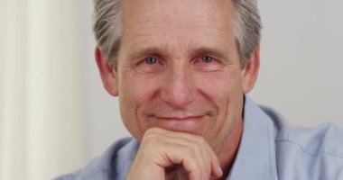 Kıdemli adam yakından gülümsüyor.