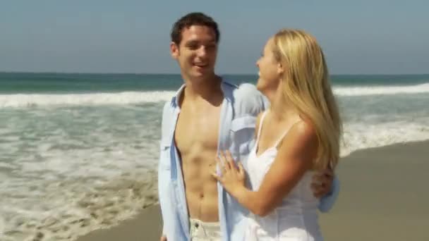 一对年轻夫妇在海边沿着海岸线散步的时候笑了 — 图库视频影像