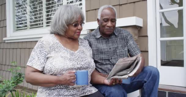 African Senior Couple Sitting Reading Newspaper Together — Stock Video