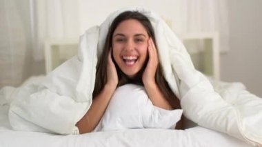 Neşeli genç beyaz kadın çarşaflardan fırlıyor.