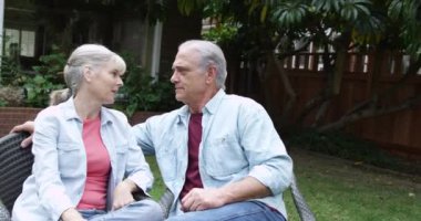 Yaşlı çift bahçede oturmuş konuşuyor.