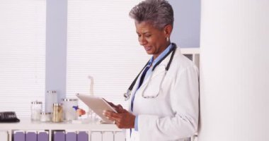 Mutlu siyah kıdemli doktor ofisinde tablet ile ayakta