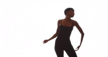 Siyah kadın beyaz arka planda zarif dans ediyor.