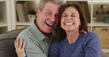 Mutlu yaşlı çift kanepede sarılıyor.