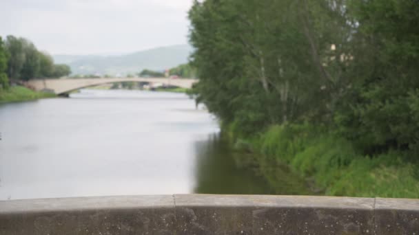 フィレンツェイタリアのアルノ川の緑と橋の背景プレート ヨーロッパの川の水の風光明媚な景色の前のセメントレールの焦点画像で — ストック動画