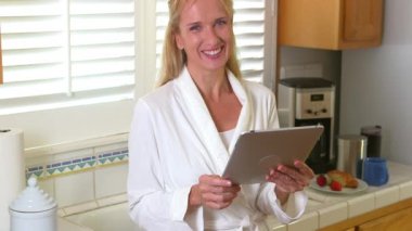 Sabah hazırlanırken tablet kullanan mutlu kadın.