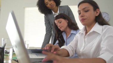 Dizüstü bilgisayarda birlikte çalışan bir grup iş kadını.