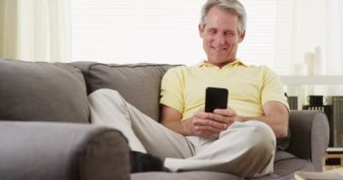 Son sınıf öğrencisi akıllı telefondan gülümsüyor.