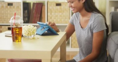 Kahve masasında tablet kullanan mutlu melez kadın.