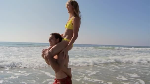 Young Couple Beach Giving Piggy Back Rides — Stock Video