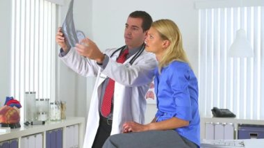 Erkek doktor hastanın röntgenini inceliyor.