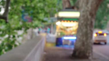 Odaklanamadığı sokak sahnesi Avrupa 'da kaldırımda duruyor. Yiyeceklerin bulanık arkaplanı sokak kenarındaki büyük ağacın altında duruyor.