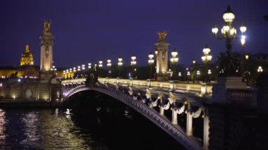 Avrupa 'daki tarihi Fransız köprüsünün arka planında gece ışık direkleri açık. Paris 'teki Seine Nehri' nin karşısındaki 3. Alexandre 'nin odaklanmış görüntüsü
