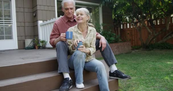 快乐的老夫妇坐在院子里的门廊上聊天 — 图库视频影像
