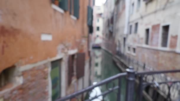 イタリアのヴェネツィアで古い家や狭い運河のぼやけたショット 緑の窓のシャッターでイタリアの建物の橋からの控えめな眺め — ストック動画