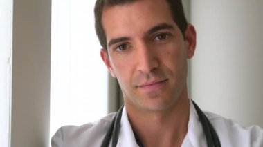 Pencerenin yanında başarılı bir erkek doktor duruyor.