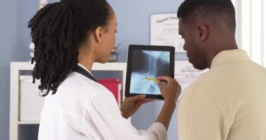 Afro-Amerikan hasta kadın doktor ile x ışınları hakkında tablete konuşuyor.