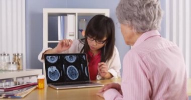 Asyalı Doktor beyin taramaları için yaşlı hasta açıklayan