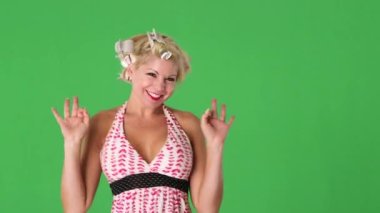 Saçında bigudileri olan genç bir kadın komiklik yapıp öpücükler saçıyor.