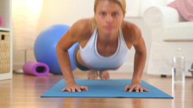 Şınav çeken ve kameraya bakan sağlıklı bir kadın.