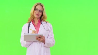 Kadın doktor gülümsüyor ve panoya yazı yazıyor.