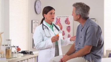 Kadın doktor yaşlı adama ilaç yazıyor.