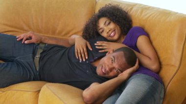 Afro-Amerikalı kadın ve erkek kanepede yatıyor.
