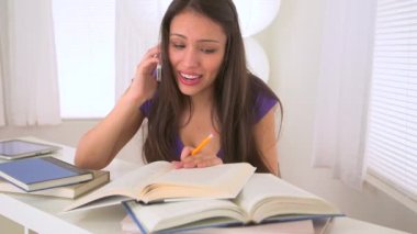 Meksikalı kadın ödev yapıyor ve akıllı telefondan konuşuyor.