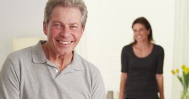 Kameraya bakarak oturma odasında ayakta mutlu yaşlı çift