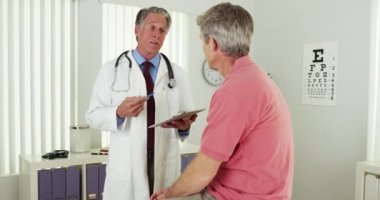 Kıdemli doktor yaşlı bir hastayla konuşuyor.