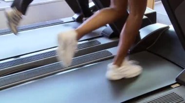 Spor salonunda koşu bandında koşan iki genç bayan arkadaş.