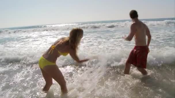 若いカップルが飛び散って海で遊ぶ — ストック動画