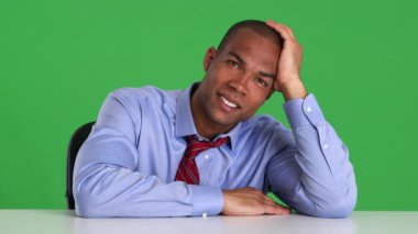 Masada oturan gülümseyen genç yöneticinin portresi.