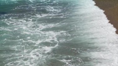 Küçük dalgalar yavaşça kıyıya vuruyor.