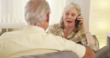 Akıllı telefondan konuşan olgun bir kadın partneriyle oturuyor.