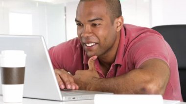 Masada dizüstü bilgisayar kullanan gülümseyen adam.