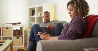 Siyah çift kanepede elektronik aygıtlar kullanarak