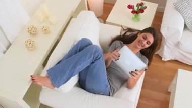 Mutlu kadın kanepede ipad kullanıyor.