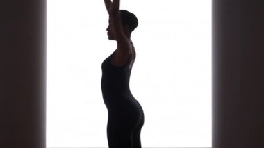 Parlak ışığın önünde dans eden siyah kadın