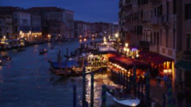 Şehir ışıklarının panoramik manzarası ve Rialto Köprüsü 'nden Büyük Kanal boyunca renkli binalar. Kanalda seyahat eden gondolların bulanık arka planı ve geceleri alışveriş yapan turistlerin. 4k