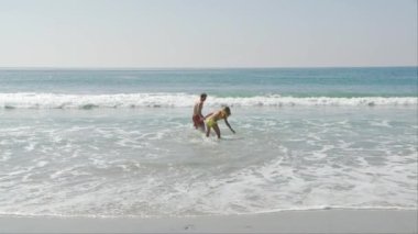 Sahilde okyanusta oynayan genç bir çift.