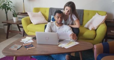 Afro-Amerikalı ve Kafkasyalı sevgili dizüstü bilgisayarla faturaları ödüyor. Milenyum çifti oturma odasında oturmuş evrak işleriyle uğraşıyor. 4k Yavaş çekim el bilgisayarı