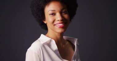 Flört eden siyah kadın kameraya bakıyor ve gülümsüyor.