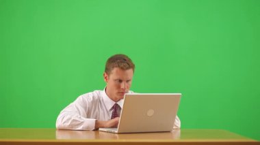 İş adamı masada oturmuş kollarını kaldırarak kutlama yapıyor.