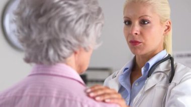 Yaşlı bir hastanın omzunda eli olan bir doktor.