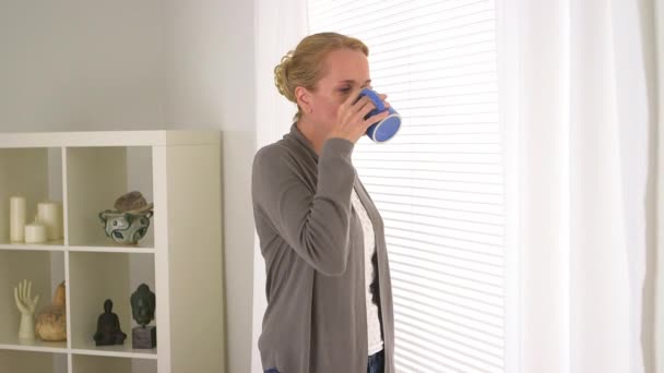 一个成熟的女人看着窗外喝茶 — 图库视频影像