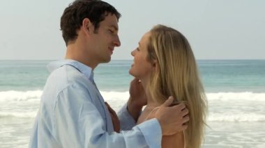 Genç çift okyanusun kenarında öpüşüyor.