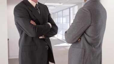 Ayakta duran ve konuşan iki iş adamının orta çekimi.